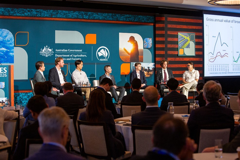 A panel on a raised stage speaking in front of an audience