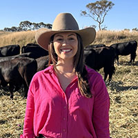 Claire Taylor standing in front of a field of cattle