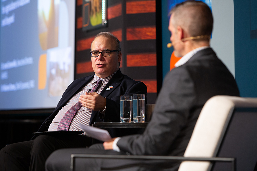 Two people sitting on a stage in conversation 