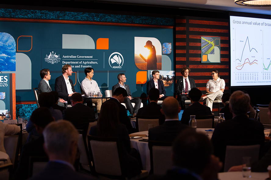 A panel of 7 sitting on stage presenting to an audience