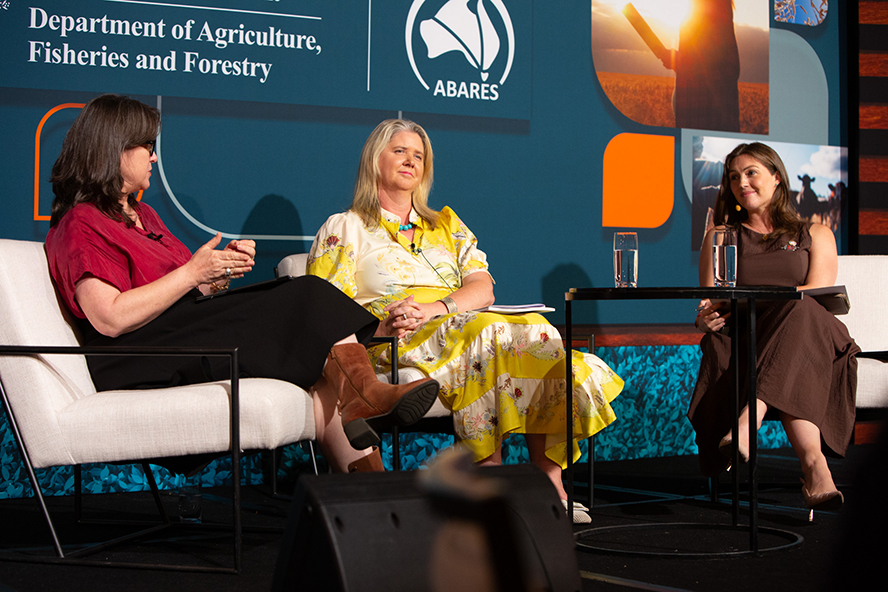 Three people sitting on a stage in conversation