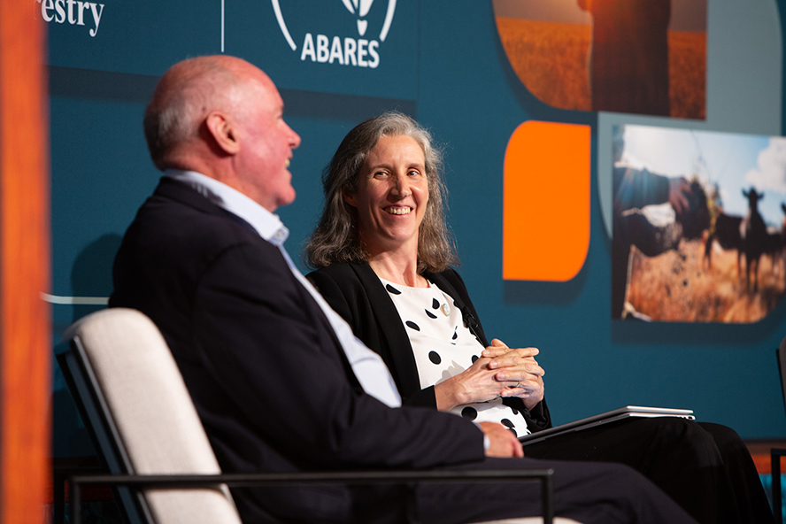Two people sitting on a stage in conversation 