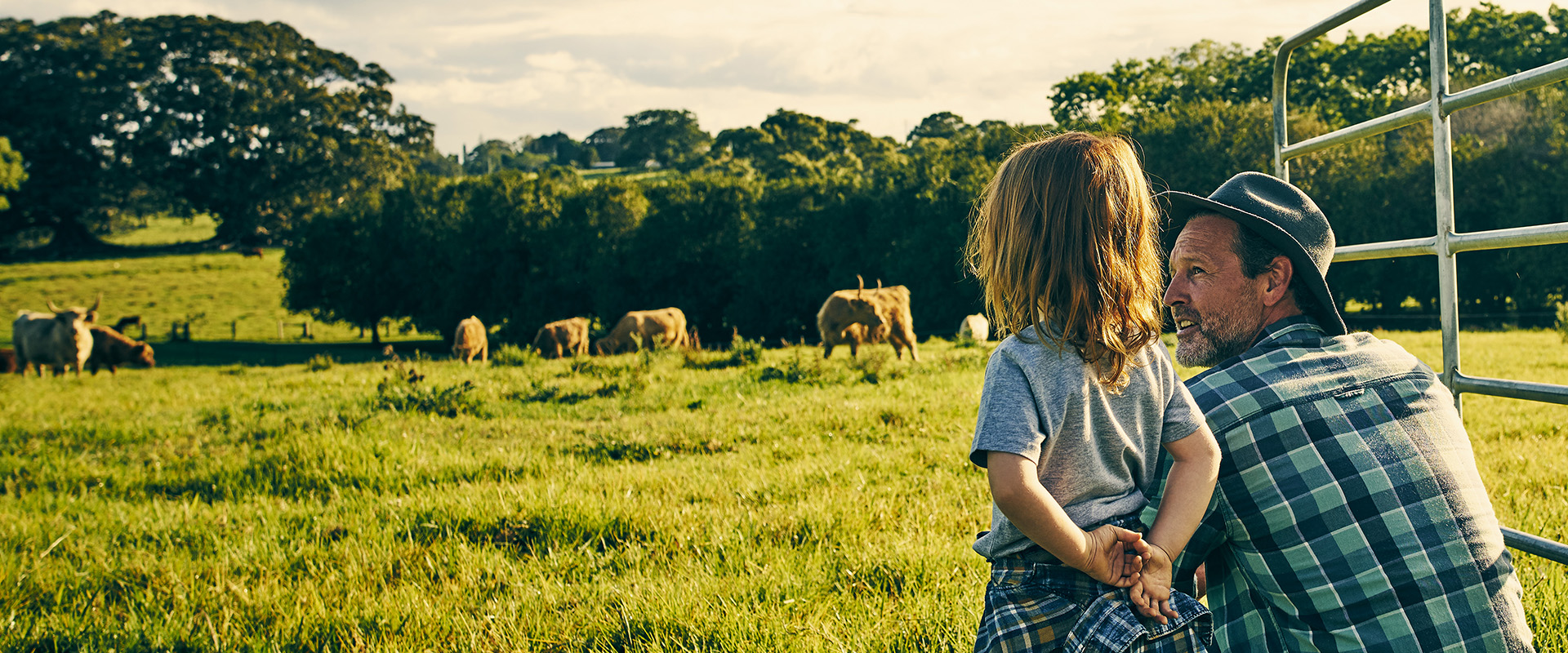 A farmer and a child in a field looking at cattle