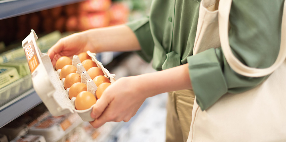 A consumer looking at a carton of eggs in a supermarket