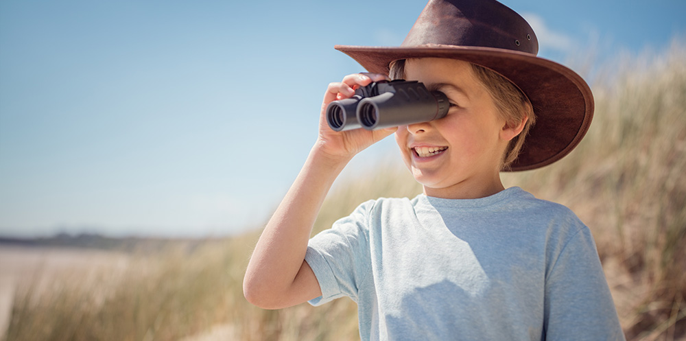 A young boy looking through binoculars
