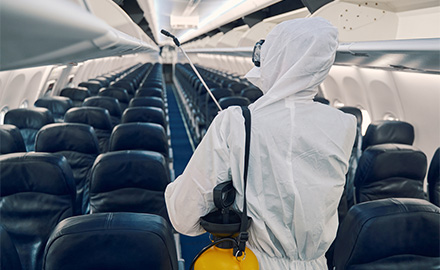 Image of a person in a white protective suit using a spray to disinsect an aircraft cabin