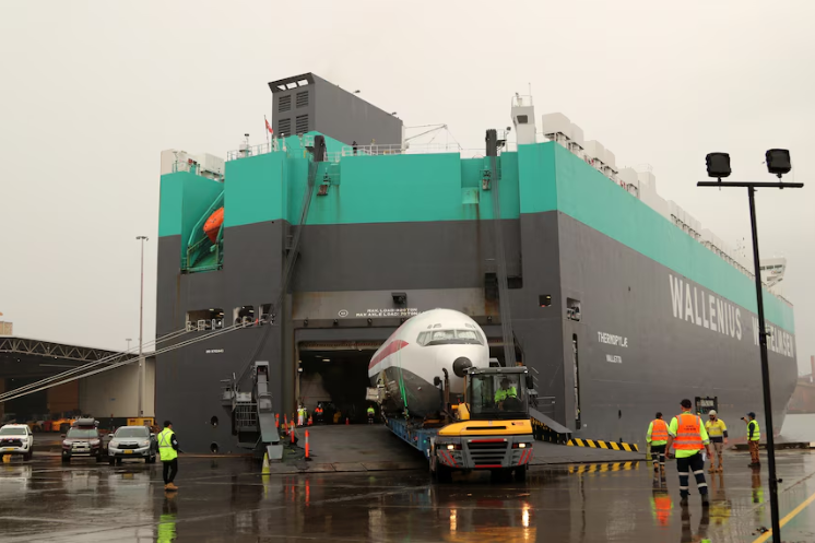 A boeing airplane being loaded onto a cargo vessel