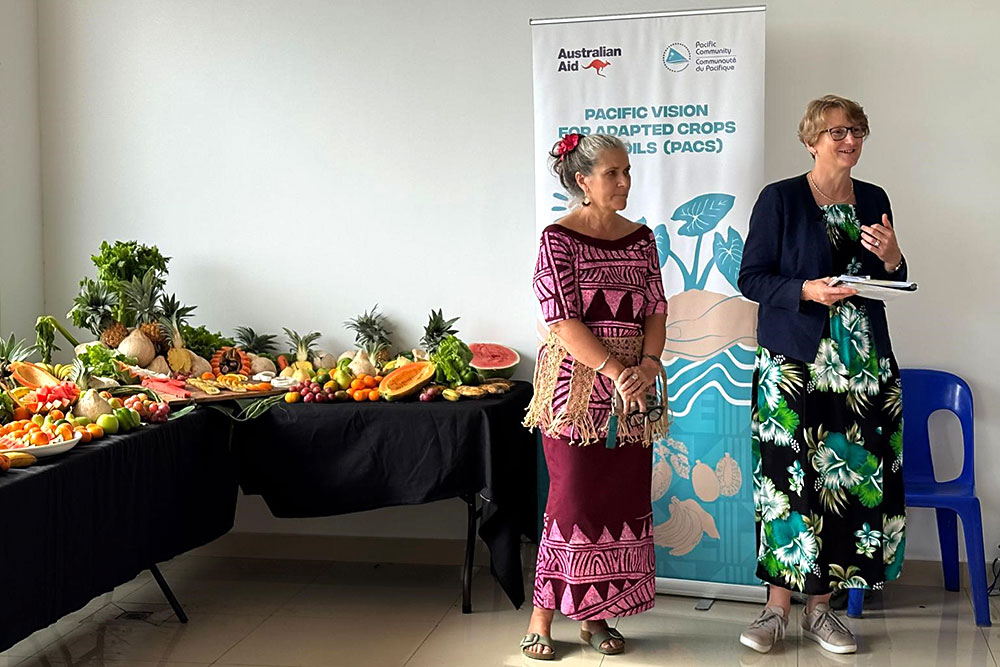 Tina Hutchison, head of Australia’s delegation and DAFF Deputy Secretary, and Karen Mapusua, Director of SPC’s Land Resources Division, spoke at the launch of the Pacific Vision for Adapted Crops and Soils (PACS). The event featured a display of tropical fruit and a promotional banner in the background.