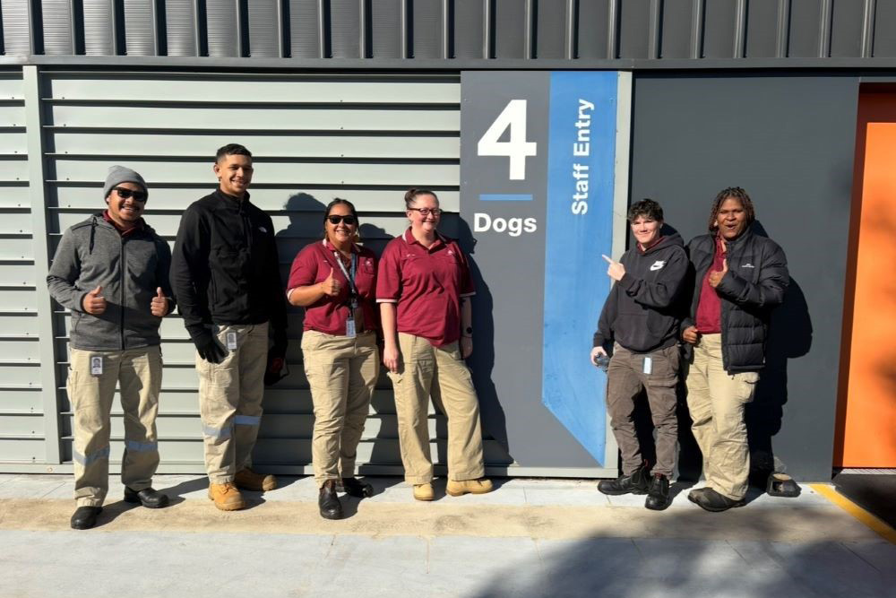 6 First Nations biosecurity trainees standing outside the department's dog kennels at the peq facility