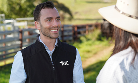 Two people standing near a livestock fence