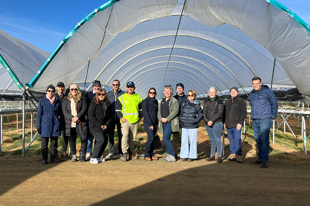 Image of a group of people standing in front of a greenhouse