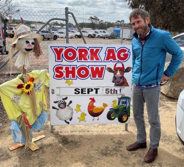 A person standing next to a scarecrow and a sign saying "York Ag Show, Sept 6th"