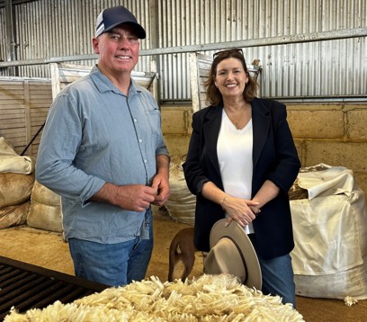 Two people standing inside a large shed amongst wool bales