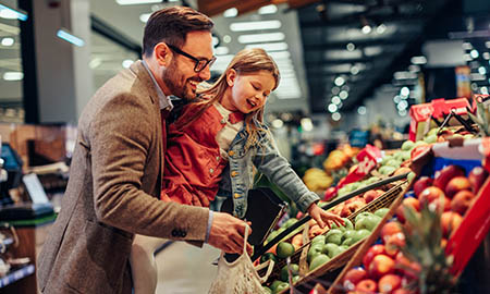 An adult and child in a supermarket shopping for fruit
