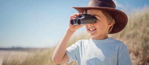 A young boy looking through binoculars