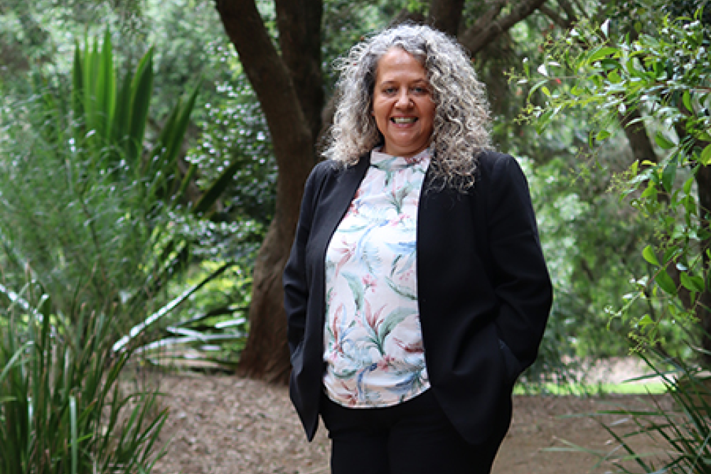 Image of a person standing in front of a tree and smiling at the camera.