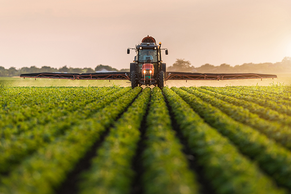 Image of a tractor irrigating a green field