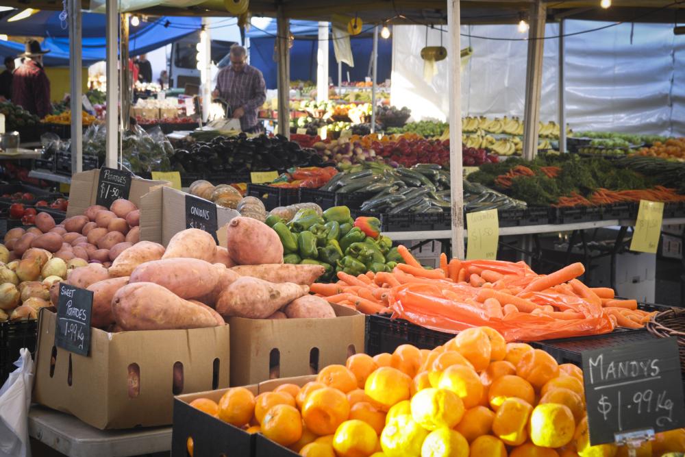 Boxes of fruit and vegetables for sale are stacked on tables at a market