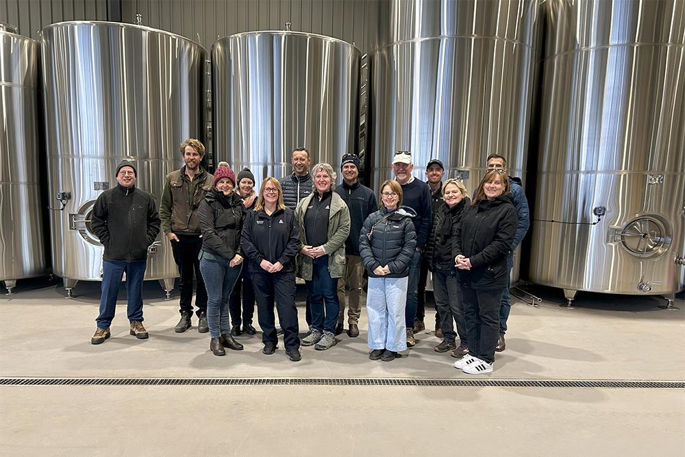Image of a group of people standing in front of wine vats