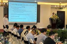 Vietnamese bosecurity students sitting at a long conference desk in front of a presentation screen and male presenter.
