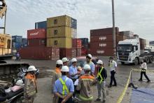 Workers in hard hats standing on a dock full of shipping containers