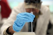 Indigenous ranger using a pipette in a lab with a gloved hand.